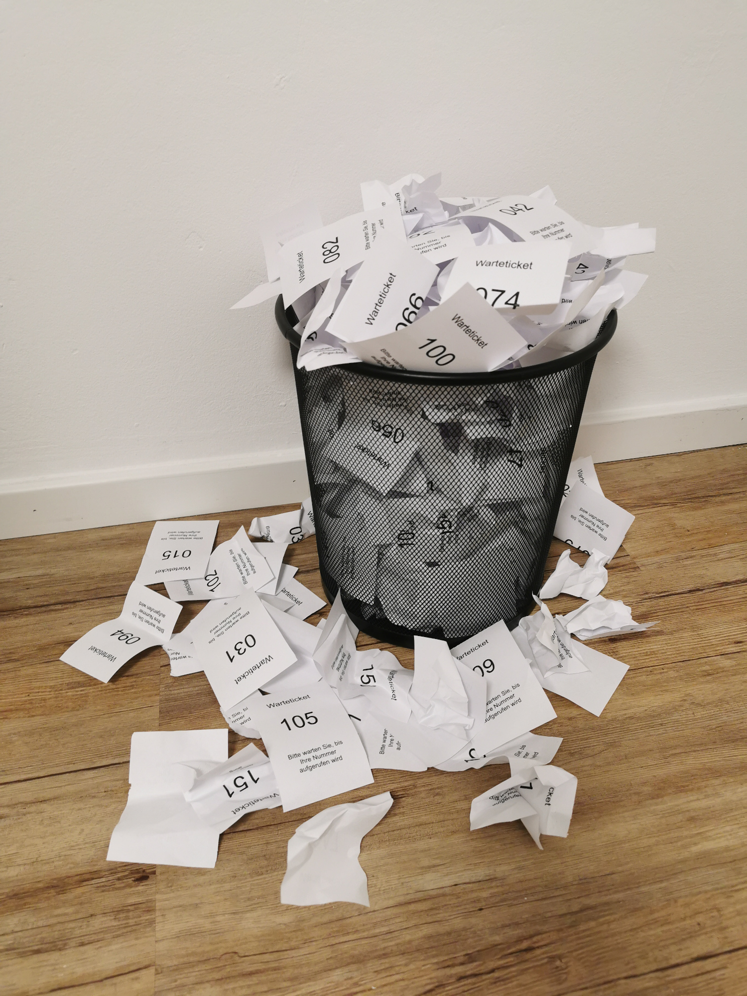 Mülleimer voller gedruckter Wartemarken zum Patientenaufruf nicht nachhaltig